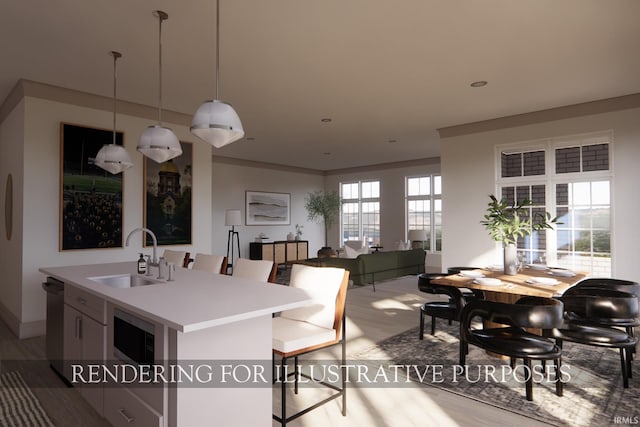 kitchen with decorative light fixtures, sink, a wealth of natural light, and an island with sink