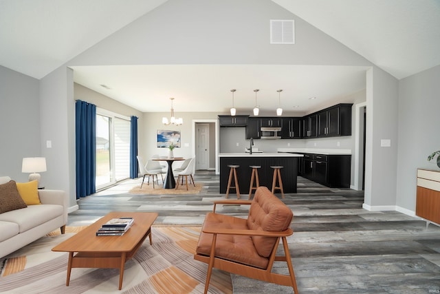 living room with an inviting chandelier, vaulted ceiling, dark hardwood / wood-style flooring, and sink