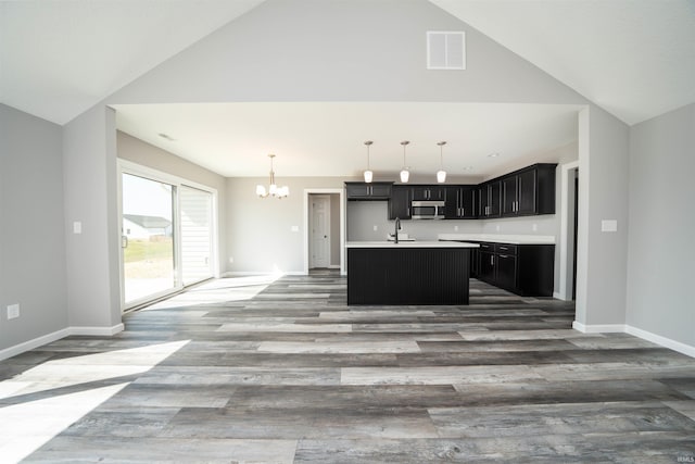 kitchen featuring a kitchen island with sink, dark hardwood / wood-style floors, sink, and lofted ceiling