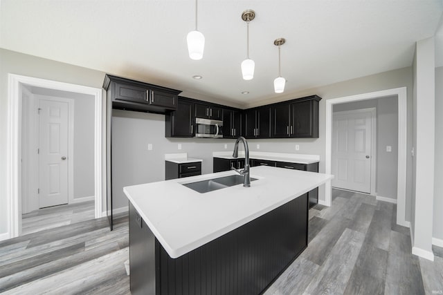 kitchen with a center island with sink, light hardwood / wood-style floors, and pendant lighting