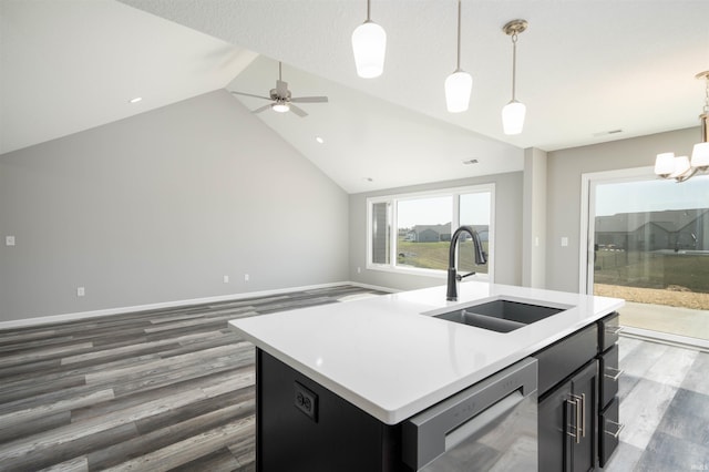 kitchen featuring dishwashing machine, hanging light fixtures, lofted ceiling, a kitchen island with sink, and sink