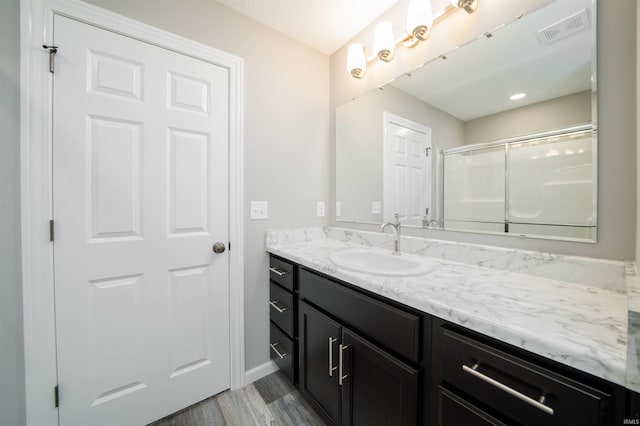 bathroom featuring a shower with shower door, hardwood / wood-style flooring, and vanity