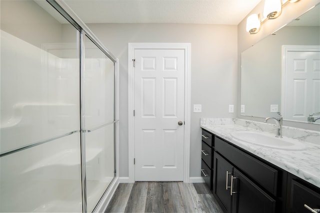 bathroom with vanity, a textured ceiling, hardwood / wood-style floors, and an enclosed shower