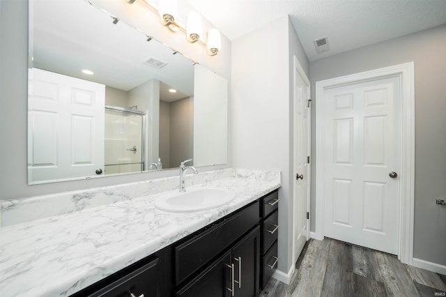 bathroom with walk in shower, vanity, and hardwood / wood-style floors