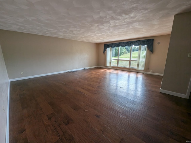 empty room with a textured ceiling and dark hardwood / wood-style flooring