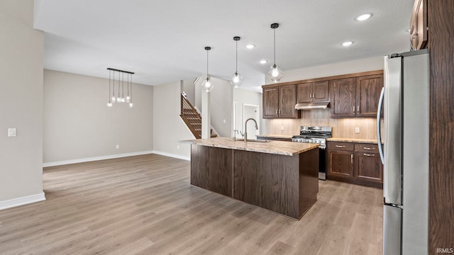 kitchen featuring pendant lighting, sink, a center island with sink, light hardwood / wood-style flooring, and appliances with stainless steel finishes