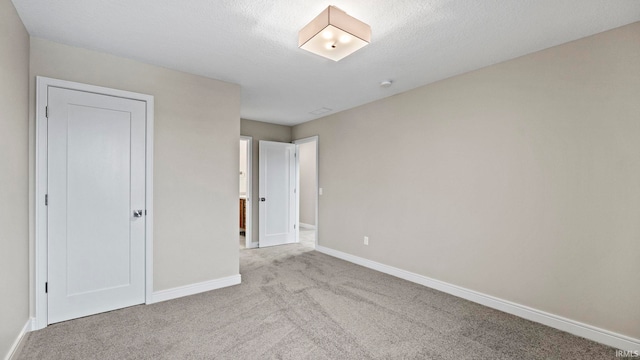 unfurnished bedroom featuring a textured ceiling, light colored carpet, and a closet