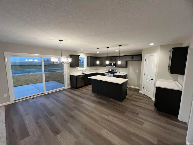 kitchen featuring stainless steel appliances, dark hardwood / wood-style floors, a center island, hanging light fixtures, and sink