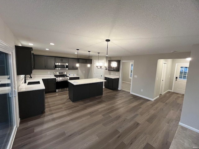 kitchen with a kitchen island, sink, hanging light fixtures, appliances with stainless steel finishes, and dark wood-type flooring