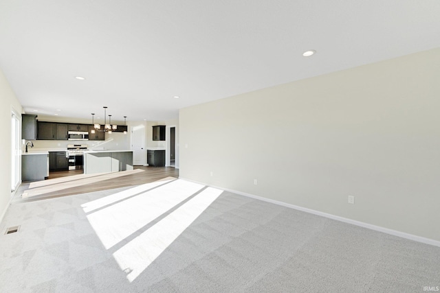 unfurnished living room with recessed lighting, baseboards, visible vents, and light colored carpet