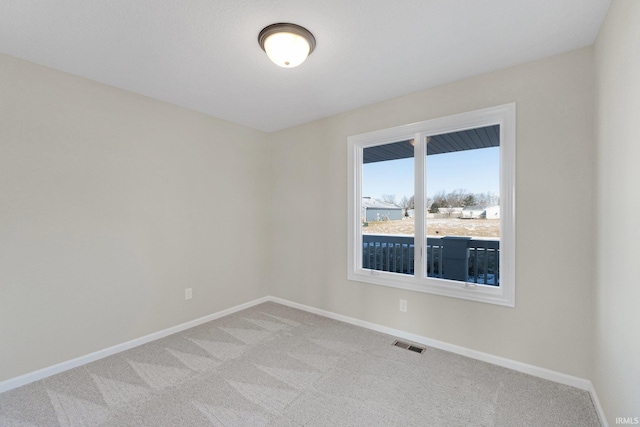 empty room featuring baseboards, visible vents, and light colored carpet