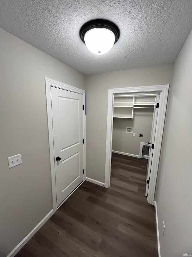 corridor with dark hardwood / wood-style floors and a textured ceiling