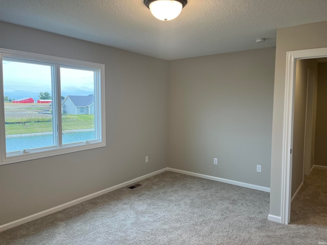 carpeted spare room featuring a textured ceiling