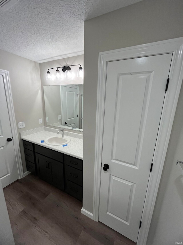 bathroom featuring hardwood / wood-style floors, vanity, and a textured ceiling