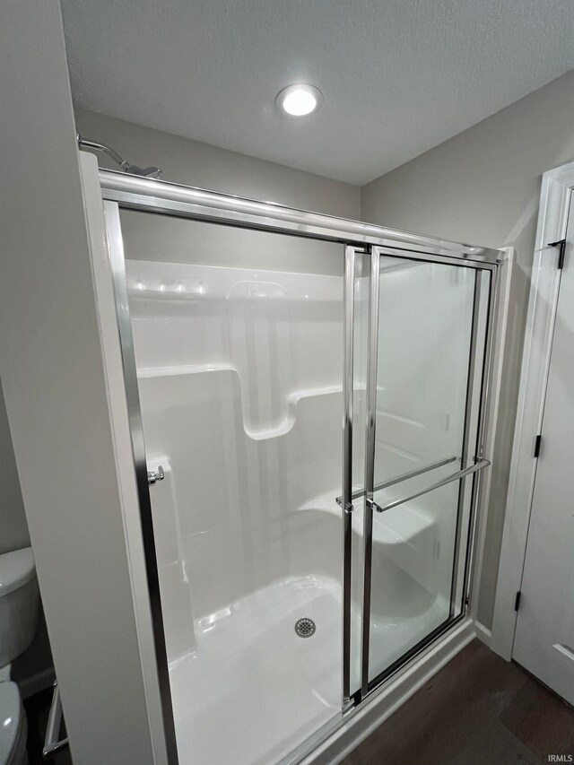 bathroom featuring toilet, an enclosed shower, and hardwood / wood-style floors