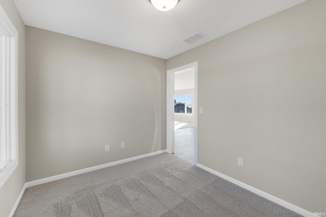 empty room featuring carpet floors, visible vents, and baseboards