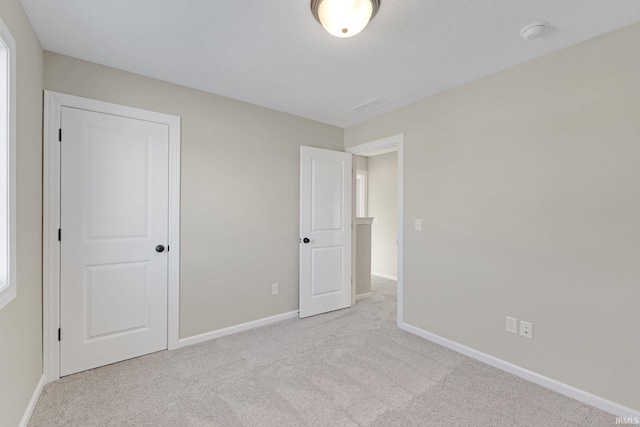 unfurnished bedroom with carpet floors, visible vents, and baseboards