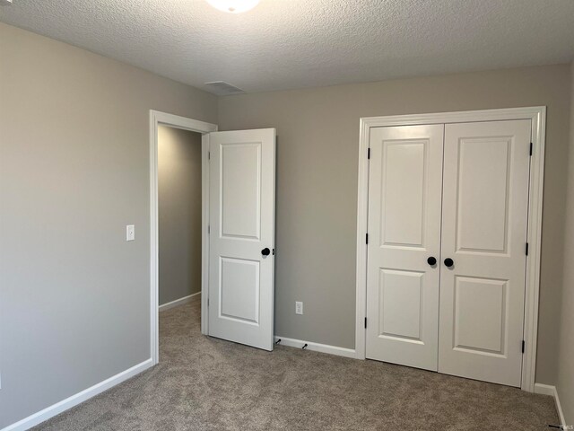 unfurnished bedroom with light colored carpet, a textured ceiling, and a closet