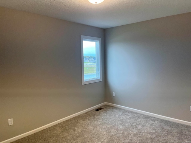 empty room with a textured ceiling and carpet flooring