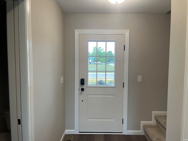 doorway with dark wood-type flooring and a textured ceiling