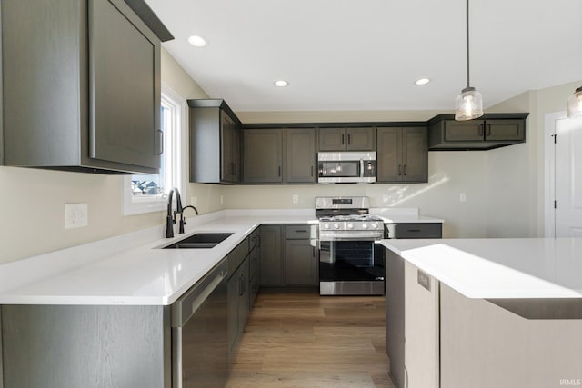 kitchen featuring recessed lighting, wood finished floors, appliances with stainless steel finishes, and a sink