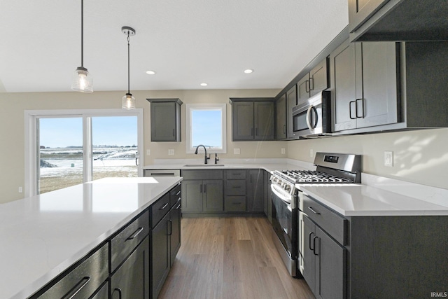 kitchen featuring a sink, stainless steel appliances, light wood finished floors, light countertops, and recessed lighting