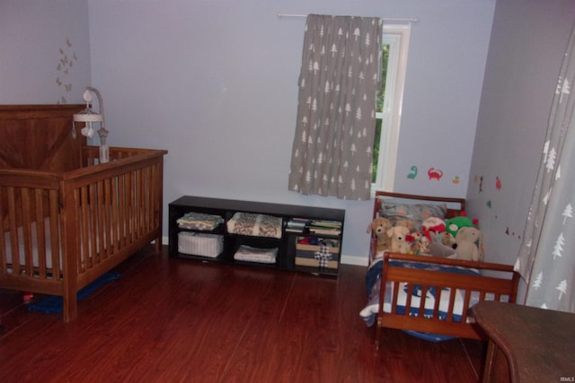 bedroom featuring a crib and dark hardwood / wood-style floors