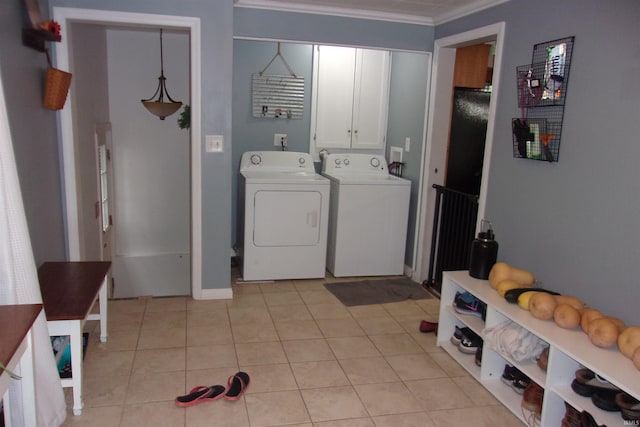 laundry area featuring cabinets, light tile patterned floors, washer and clothes dryer, and crown molding