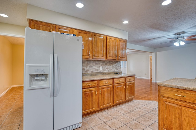 kitchen featuring backsplash, light tile patterned floors, a textured ceiling, ceiling fan, and white fridge with ice dispenser