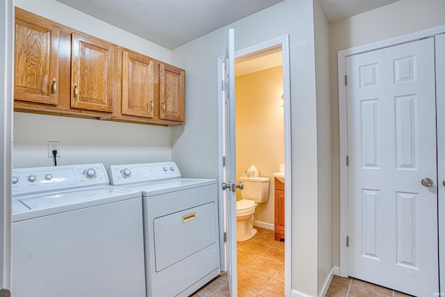 washroom with washer and clothes dryer, cabinets, light tile patterned floors, and a textured ceiling