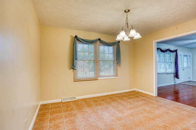 spare room with a textured ceiling, a chandelier, and hardwood / wood-style flooring