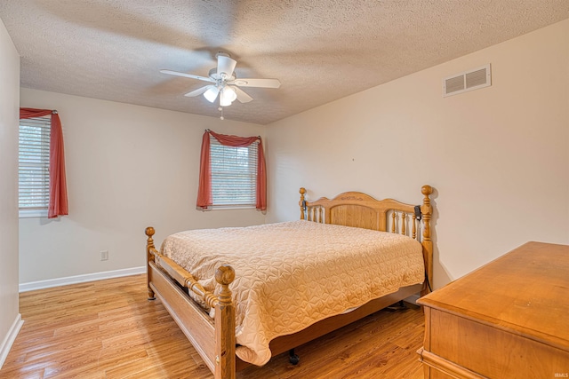 bedroom with light hardwood / wood-style flooring, ceiling fan, and a textured ceiling