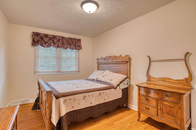 bedroom featuring a textured ceiling and light hardwood / wood-style floors