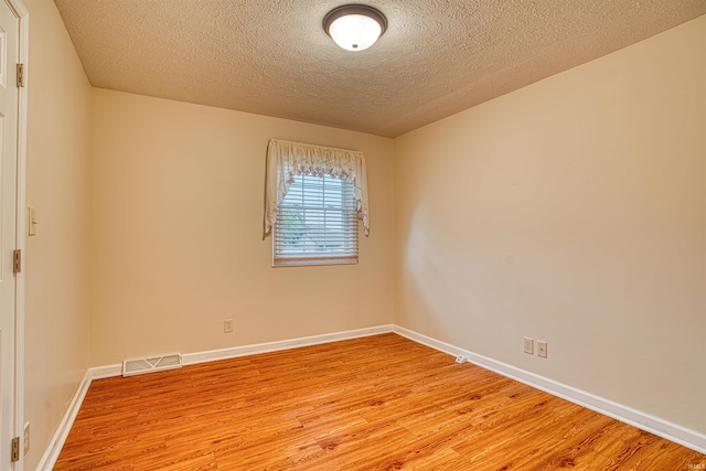 unfurnished room with light wood-type flooring and a textured ceiling