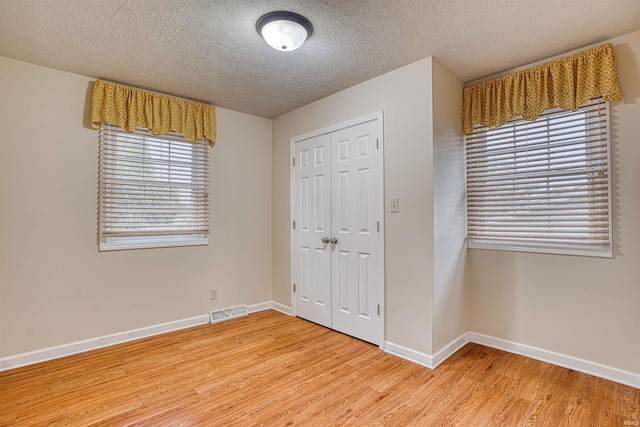 unfurnished bedroom with a closet, hardwood / wood-style floors, and a textured ceiling