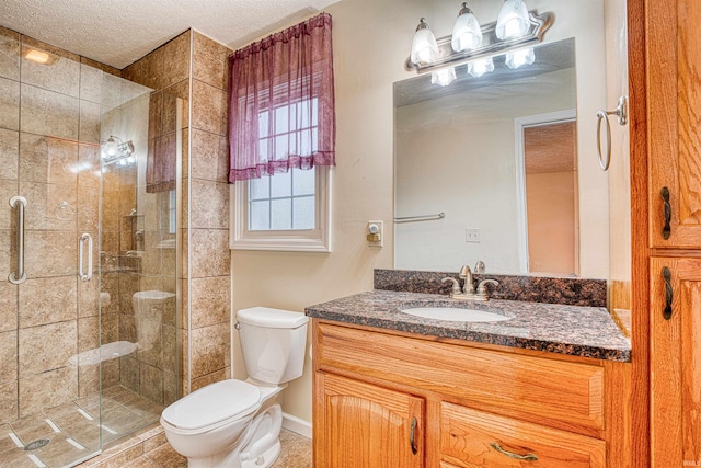 bathroom featuring a textured ceiling, a shower with door, vanity, and toilet