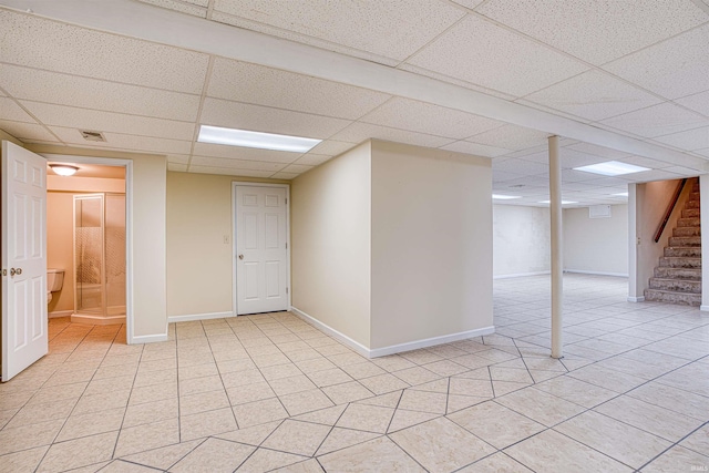 basement with a drop ceiling and light tile patterned floors