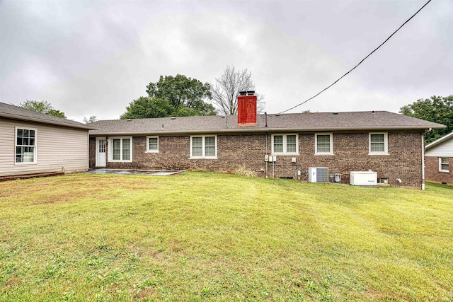 back of house with cooling unit and a yard