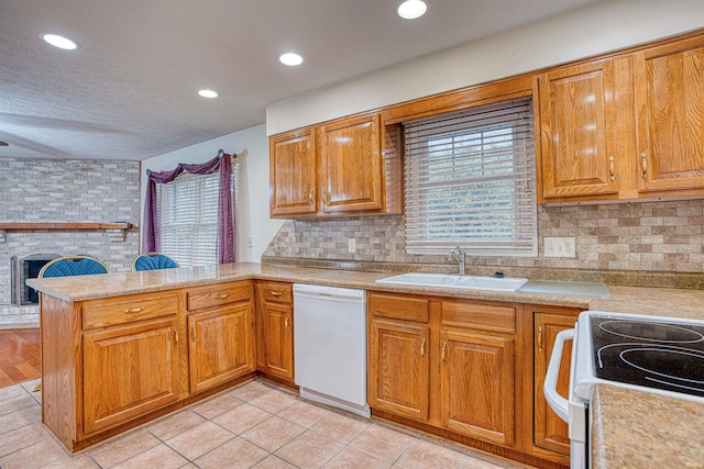 kitchen with white dishwasher, sink, kitchen peninsula, and a wealth of natural light