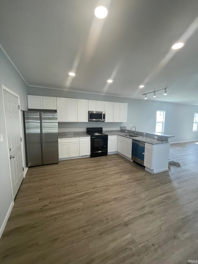 kitchen with stainless steel appliances, dark wood-type flooring, kitchen peninsula, and white cabinetry