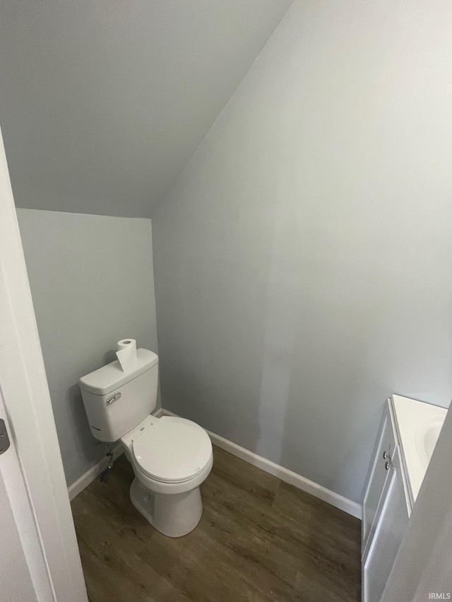 bathroom with toilet, vanity, vaulted ceiling, and hardwood / wood-style flooring