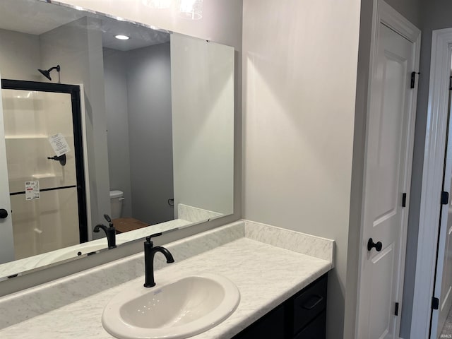 bathroom with walk in shower, vanity, and toilet