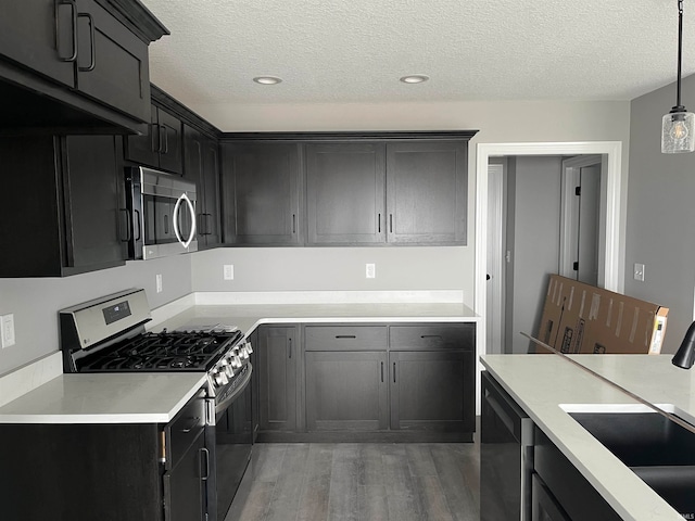 kitchen with sink, a textured ceiling, dark hardwood / wood-style floors, pendant lighting, and appliances with stainless steel finishes