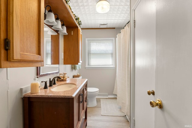 bathroom featuring hardwood / wood-style flooring, walk in shower, crown molding, vanity, and toilet