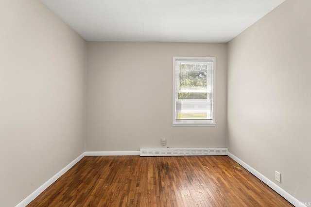 empty room featuring dark hardwood / wood-style flooring and a baseboard heating unit