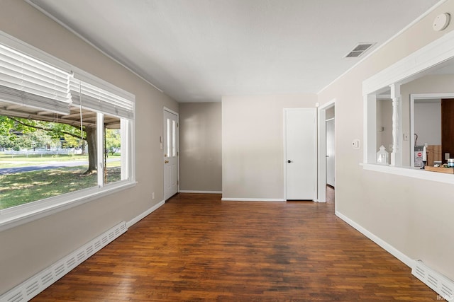 empty room featuring baseboard heating and dark wood-type flooring