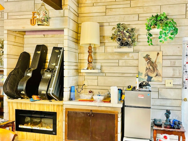 kitchen featuring tile countertops, wooden walls, and fridge