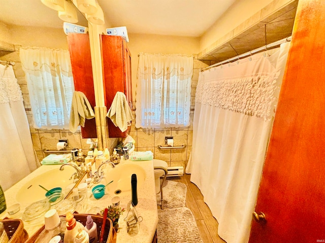 bathroom featuring hardwood / wood-style floors, a baseboard radiator, tile walls, toilet, and sink