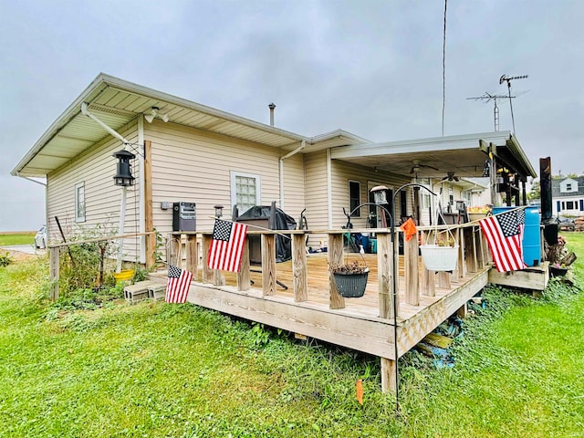 rear view of house with a wooden deck and a yard