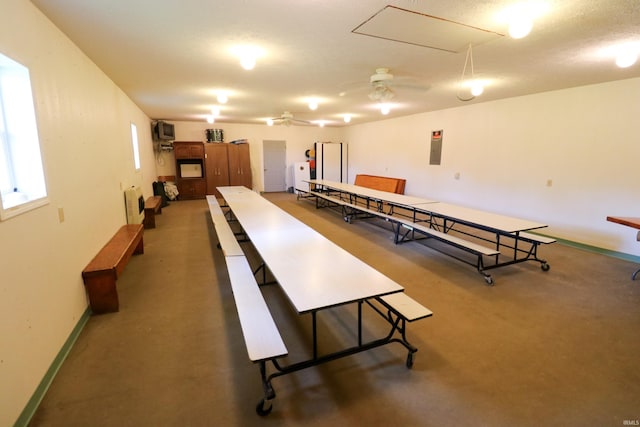 recreation room with ceiling fan, electric panel, a textured ceiling, and an AC wall unit